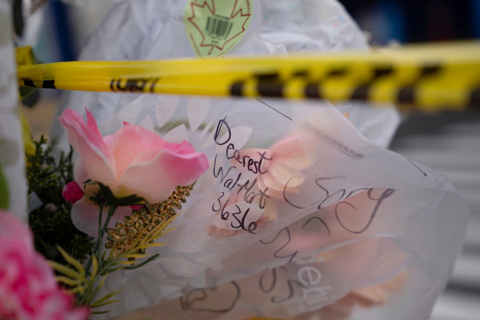 Flowers and a handwritten message at a closed Walmart following a death.