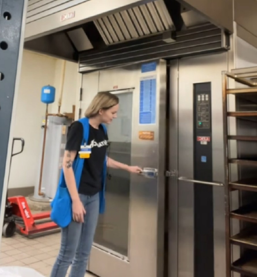 Walmart employee opening a large industrial oven.