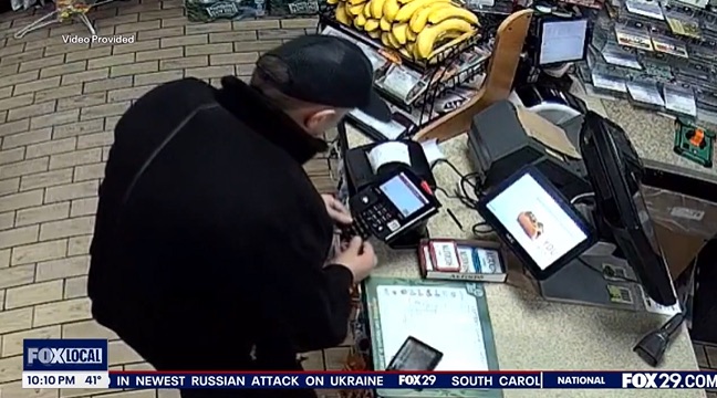 Surveillance footage of a person using a card reader at a checkout counter.