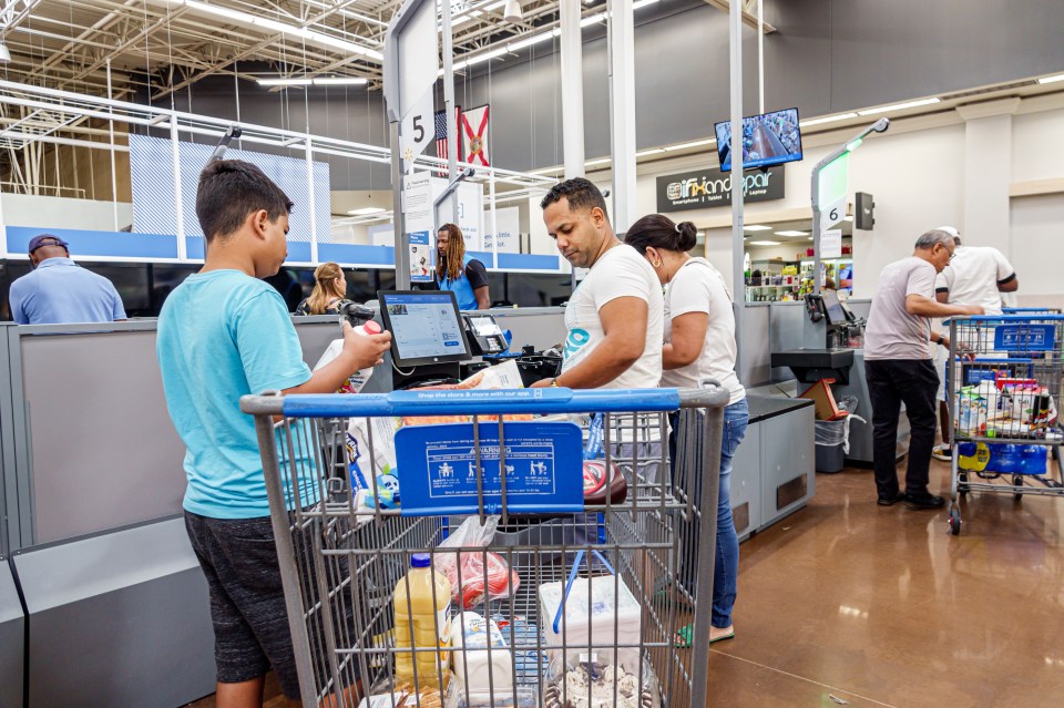 A father and son using self-checkout at a Walmart.