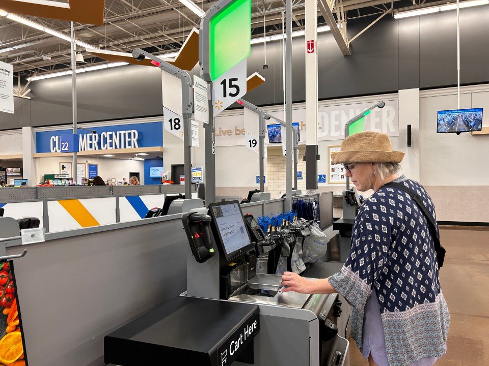 Woman using self-checkout kiosk at Walmart.