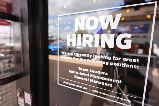 A sign announces a restaurant is hiring workers