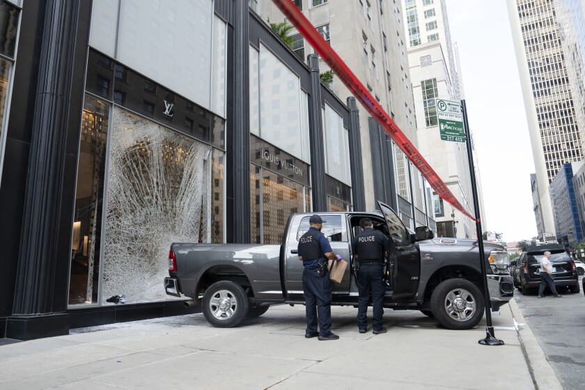 Police officers inspect a vehicle on Walton Street near North Michigan Avenue in Streeterville, Thursday, Sept. 11, 2025, after a smash and grab at the Louis Vuitton store.