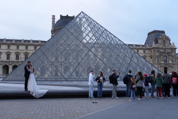 A wedding couple hugs as visitors queue to enter the...